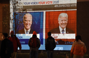 Люди смотрят на большой экран, на котором в прямом эфире отображаются результаты выборов во Флориде