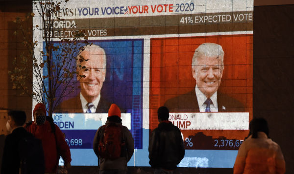 Люди смотрят на большой экран, на котором в прямом эфире отображаются результаты выборов во Флориде