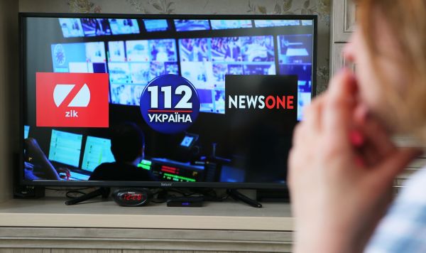 Экран телевизора с логотипами телеканалов ZIK, "112.Украина" и NewsOne, против которых Украина ввела санкции