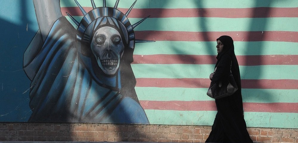 Женщина идет вдоль стены здания бывшего посольства США в Тегеране.