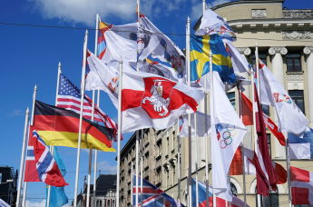 Бело-красно-белый флаг рядом с флагами стран-участниц чемпионата мира по хоккею с шайбой в Риге, Латвия, 24 мая 2021 года